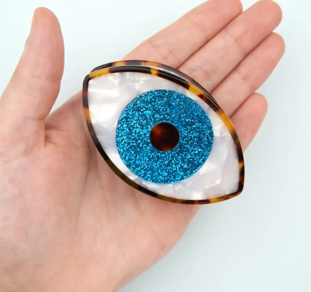 Pince Œil bleu pailleté Coucou Suzette en acétate présentée dans la main.webp