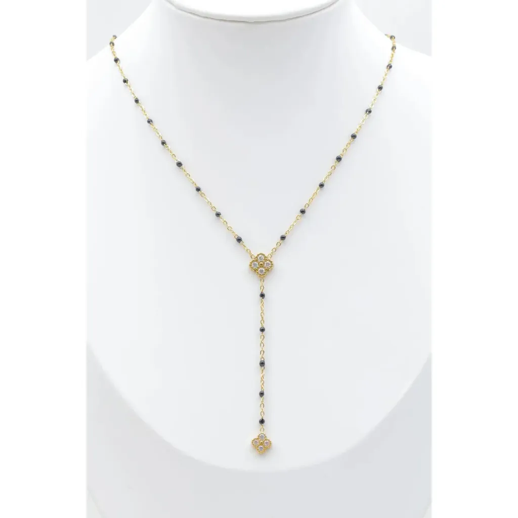 Collier lariat trèfle zircons sur chaîne perles noires, acier inoxydable doré, fond blanc.webp